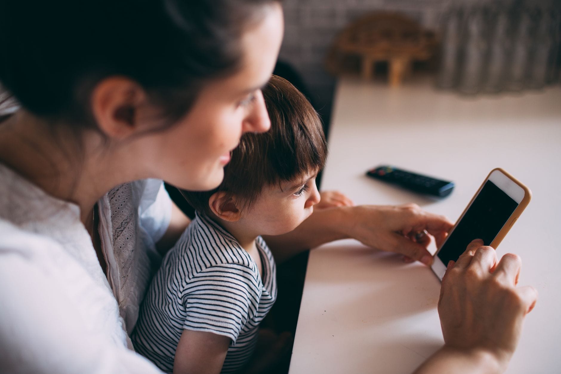 Mama z dzieckiem uczą się języka obcego przy smartfonie w domu